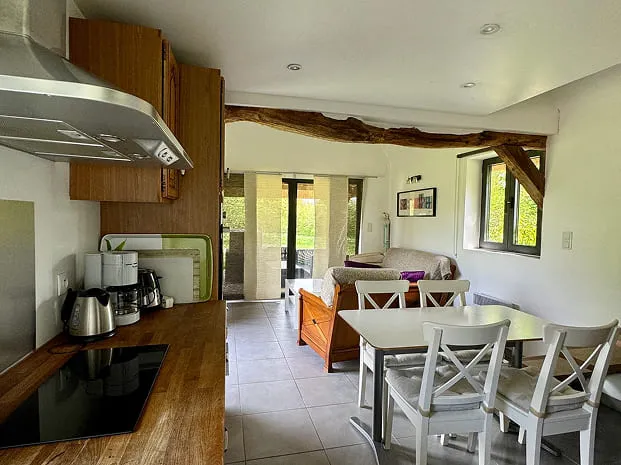 piece de vie Intérieur lumineux de La Chaumière avec cuisine équipée, coin repas et lit dans une pièce à vivre cosy et ouverte sur le jardin